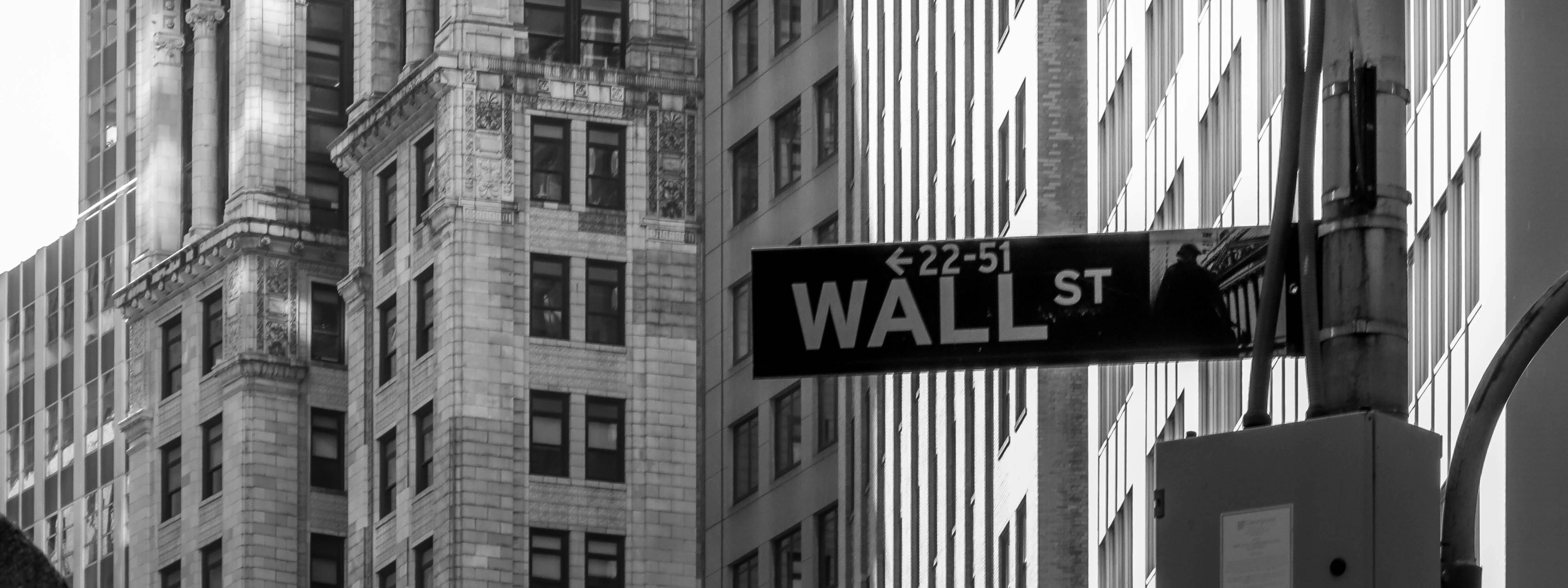Street sign for Wall Street in front of tall buildings